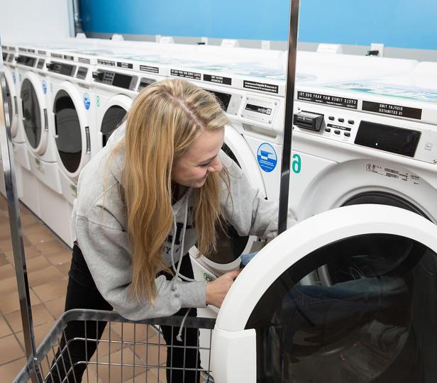 student loading laundry into a washing machine